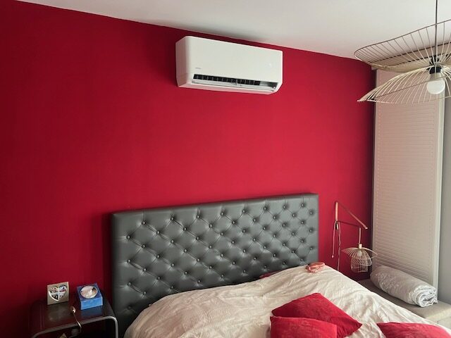 Climatisation murale sur un mur rouge dans une chambre